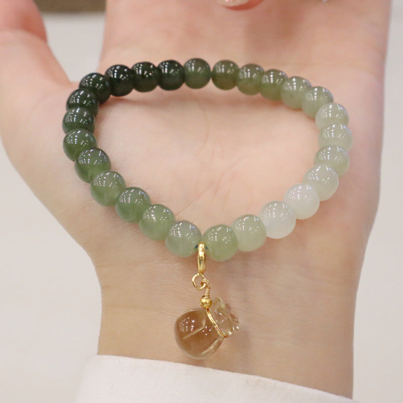 Natural Hetian Jade Gradient Bracelet with Lemon Quartz Money Bag Charm displayed on an open hand, showing the serene color transition of the jade beads.