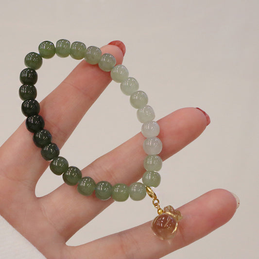 Close-up of the Hetian Jade Gradient Bracelet in a hand display, highlighting the soft green hues and lemon quartz money bag charm.