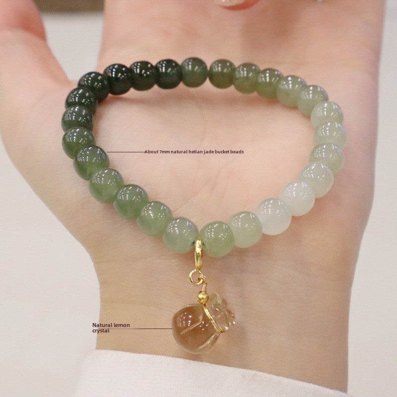 Detailed view of the Natural Hetian Jade Bracelet on a hand, featuring the gradient jade beads and a symbolic lemon quartz money bag charm.